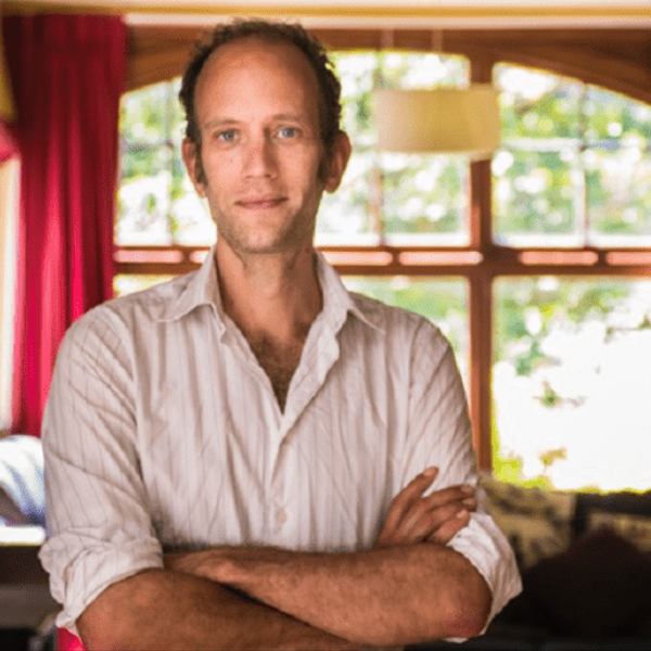 A man standing with his arms crossed and a window in the background.